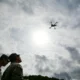 Soldiers observe a small drone flying overhead during military training in South Korea.