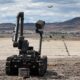 U.S. Air Force Airman 1st Class Garrett Haynie, 366th Civil Engineer Squadron explosive ordinance disposal technician, operates a bomb defusal robot while a 366th Fighter Wing F-15E Strike Eagle flies overhead at Wendover Air Field, Utah, May 20, 2022 as part of exercise Raging Gunfighter 22-2. This exercise prepares the 366th Fighter Wing for Agile Combat Employment (ACE) operations around the world. (U.S. Air Force photo by Staff Sgt. Danielle Charmichael)