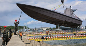 260612-N-LY640-1097 GDYNIA, Poland (June 12, 2026) – Lt. Jay Faylo, unmanned systems director of Commander Task Force 66 (CTF-66), directs the crane operator lowering a K3 Scout, an unmanned surface vessel, into the Port of Gdynia for acceptance and validation of the craft and capabilities development for project Vesuvius during exercise Baltic Operations (BALTOPS) 2026, June 12, 2026. BALTOPS 2026, the premiere maritime-focused exercise in the Baltic Sea region, provides a unique training opportunity to strengthen combined response capabilities critical to preserving freedom of navigation and security in the Baltic Sea. (U.S. Navy photo by Chief Mass Communication Specialist Sandi Grimnes Moreno)